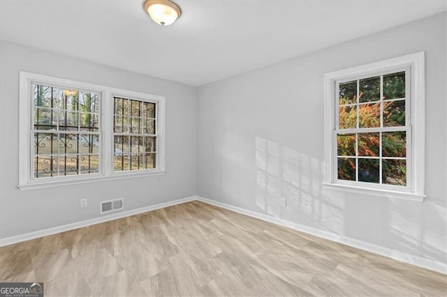 unfurnished room with a wealth of natural light, visible vents, and baseboards