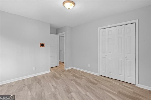 unfurnished bedroom with light wood-type flooring, baseboards, and a closet