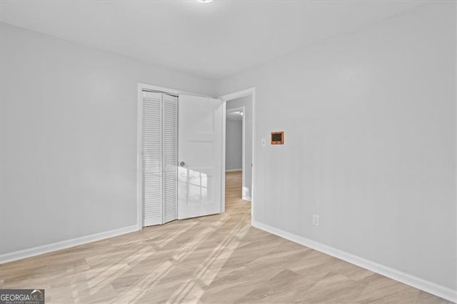 unfurnished bedroom featuring a closet, baseboards, and wood finished floors