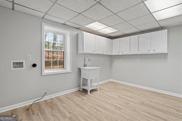 laundry area with light wood-style floors, washer hookup, cabinet space, and baseboards