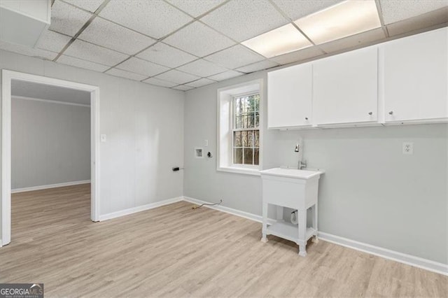 laundry room with light wood finished floors, cabinet space, and baseboards