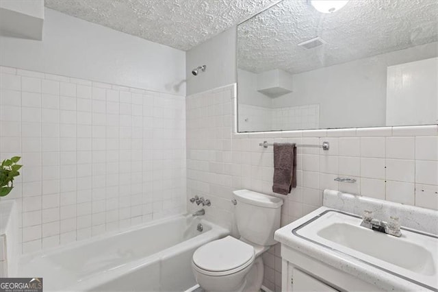 full bath featuring toilet, shower / bathtub combination, a textured ceiling, vanity, and tile walls