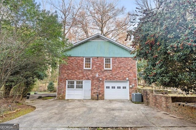 view of side of property with an attached garage, driveway, central AC, and brick siding