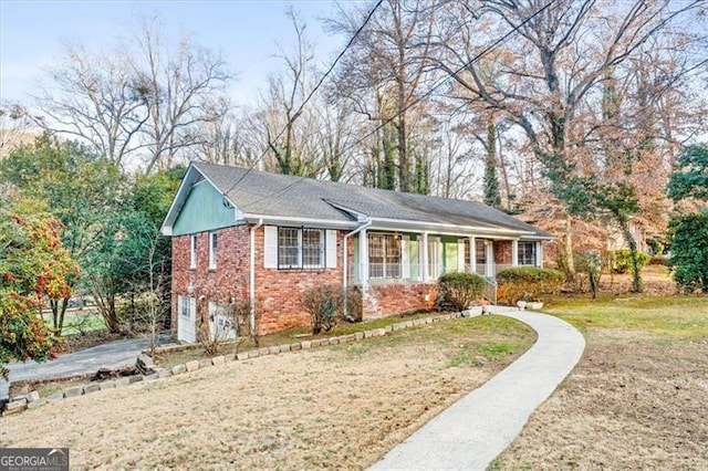 ranch-style home featuring brick siding, a front lawn, an attached garage, and aphalt driveway