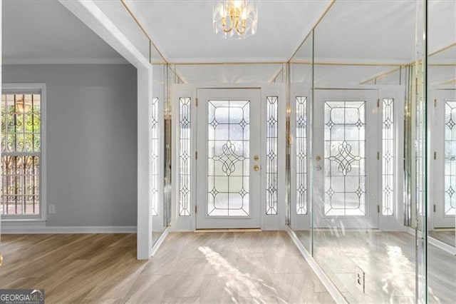 entrance foyer with a notable chandelier, baseboards, wood finished floors, and crown molding