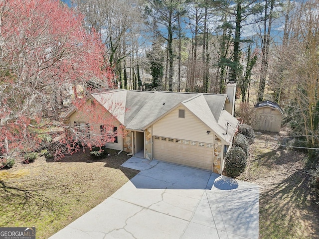 view of front facade featuring driveway, stone siding, a garage, and a chimney