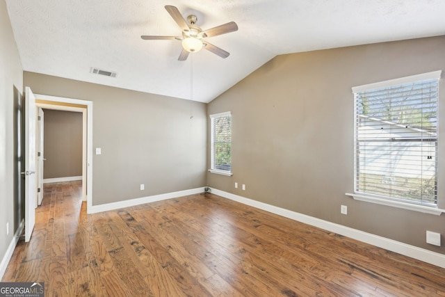 unfurnished bedroom featuring lofted ceiling, baseboards, visible vents, and wood finished floors