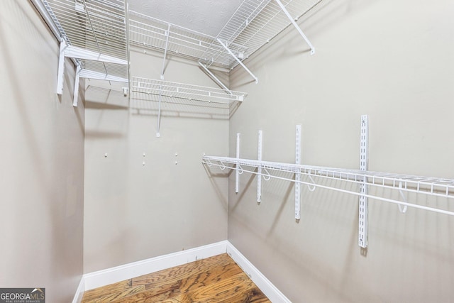 walk in closet with wood finished floors