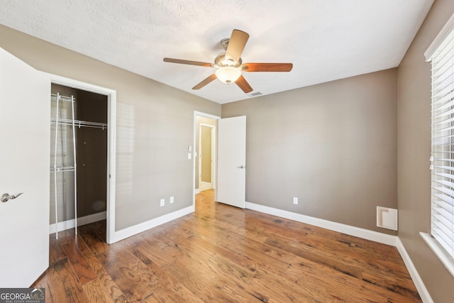 unfurnished bedroom featuring baseboards, a closet, visible vents, and wood finished floors