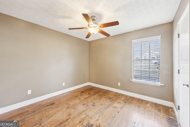 spare room featuring a textured ceiling, ceiling fan, wood-type flooring, and baseboards