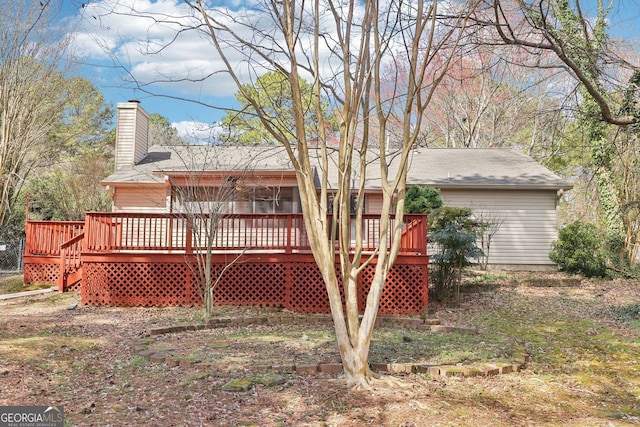 back of house with a chimney and a wooden deck