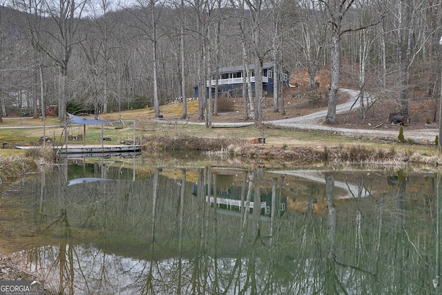 view of yard featuring a dock, a water view, and a forest view