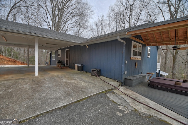 view of property exterior featuring driveway, a shingled roof, and an attached carport