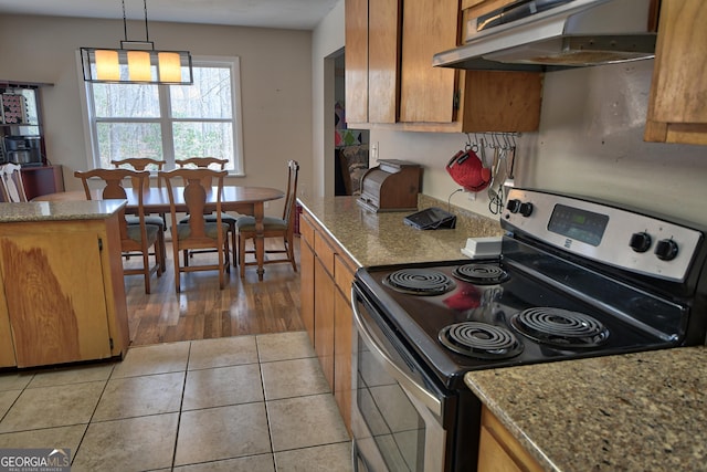 kitchen featuring light tile patterned floors, electric range, brown cabinetry, and under cabinet range hood