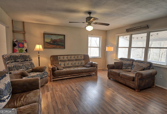 living room featuring ceiling fan, a textured ceiling, baseboards, and wood finished floors