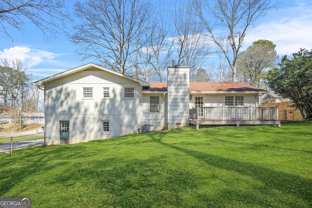 rear view of property with fence, a wooden deck, a chimney, central air condition unit, and a lawn