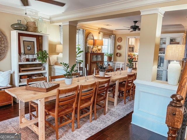 dining area featuring crown molding, dark wood-type flooring, decorative columns, and a ceiling fan