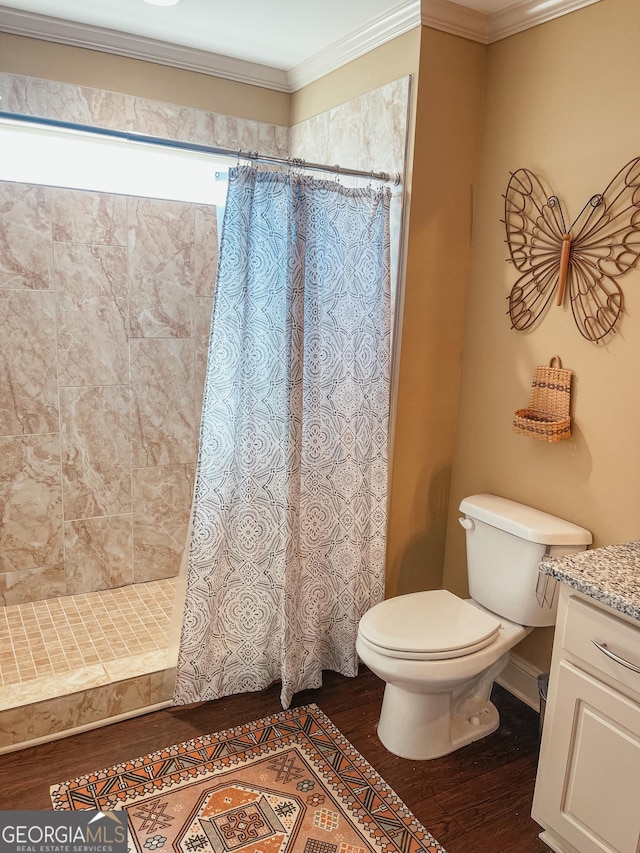 bathroom with toilet, wood finished floors, vanity, tiled shower, and crown molding