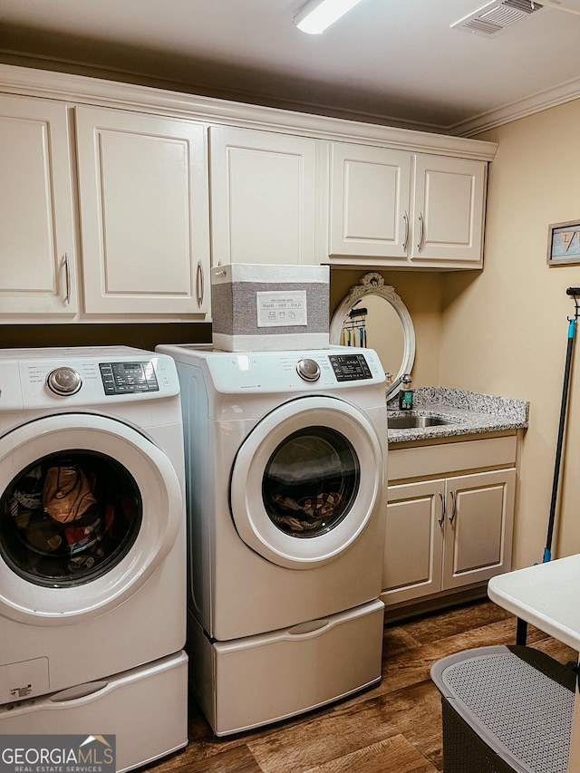 washroom with cabinet space, visible vents, dark wood finished floors, washing machine and clothes dryer, and crown molding