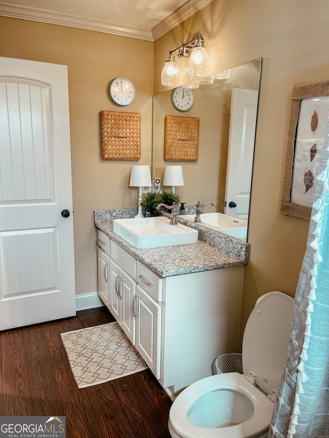 bathroom with toilet, wood finished floors, vanity, baseboards, and ornamental molding