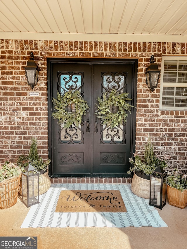 doorway to property with a porch and brick siding