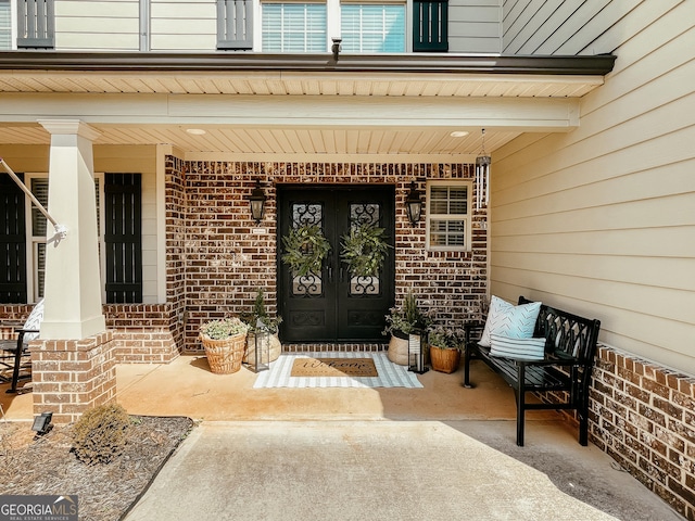 doorway to property with covered porch and brick siding