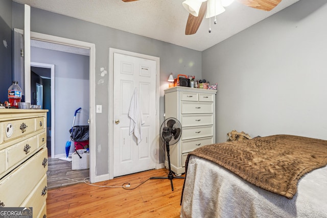 bedroom featuring a ceiling fan, light wood-type flooring, a textured ceiling, and baseboards