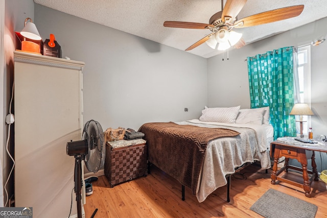 bedroom featuring a textured ceiling, ceiling fan, and light wood finished floors