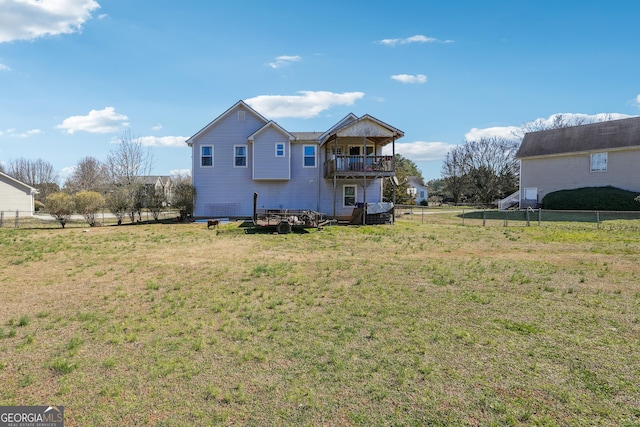 rear view of house with a yard, fence, and a balcony