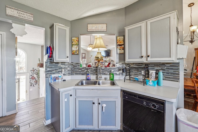 kitchen featuring black dishwasher, light countertops, vaulted ceiling, and a sink