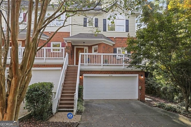 view of property with a garage, brick siding, driveway, and stairway