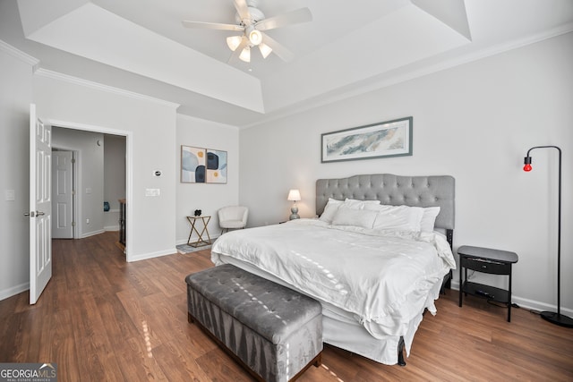 bedroom featuring a tray ceiling, wood finished floors, baseboards, and ornamental molding