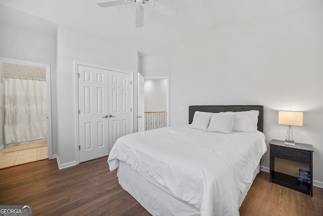 bedroom with a closet, baseboards, wood finished floors, and vaulted ceiling