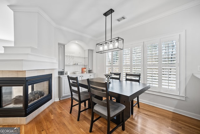 dining room with plenty of natural light, visible vents, light wood-type flooring, and ornamental molding