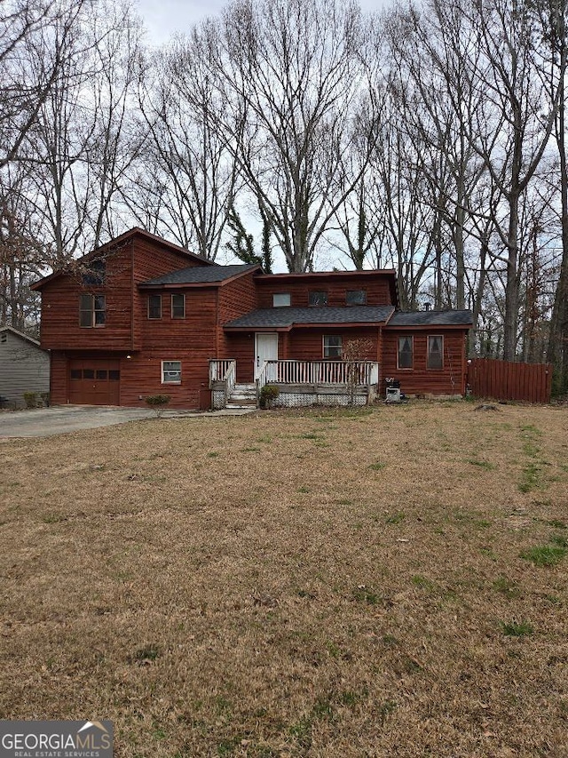 view of front facade featuring an attached garage, fence, and a front lawn