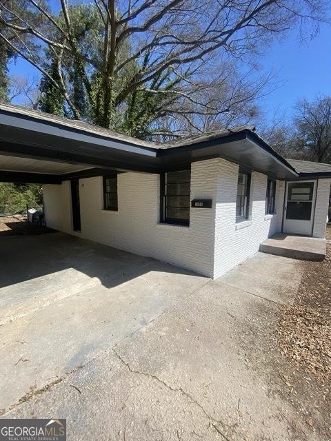 view of side of home with brick siding, an attached carport, and driveway