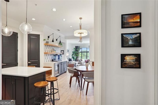 kitchen featuring beverage cooler, light wood-style flooring, light countertops, crown molding, and open shelves