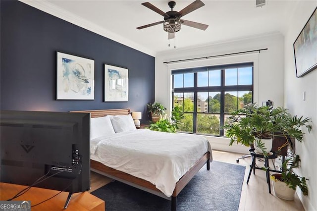 bedroom featuring ceiling fan, ornamental molding, wood finished floors, and visible vents