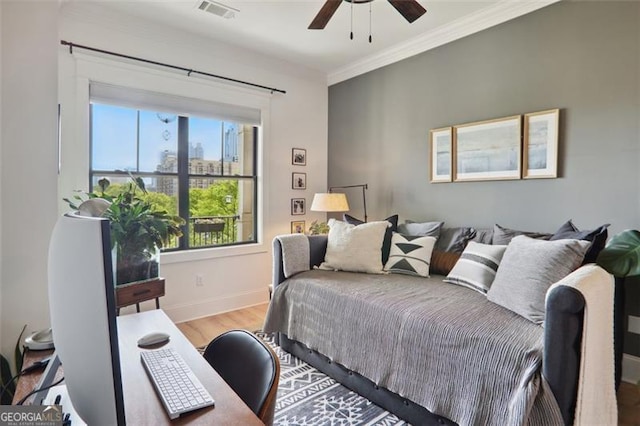 bedroom featuring crown molding, visible vents, a ceiling fan, wood finished floors, and baseboards