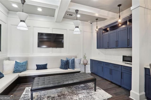 living area with a decorative wall, coffered ceiling, visible vents, dark wood-style floors, and beamed ceiling