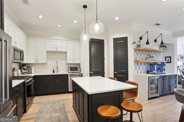 kitchen featuring white cabinets, a kitchen island, appliances with stainless steel finishes, a kitchen breakfast bar, and a sink