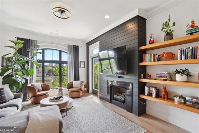 sitting room featuring a large fireplace, wood finished floors, and crown molding