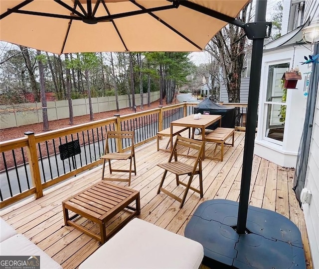 wooden terrace with outdoor dining area and fence