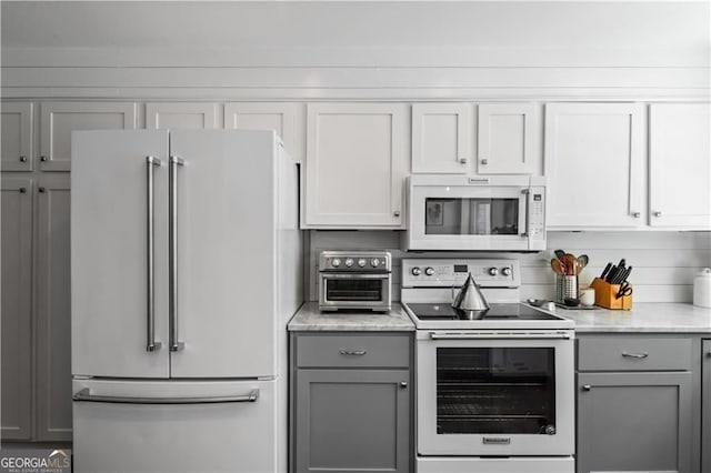 kitchen with white appliances, gray cabinets, and light stone counters