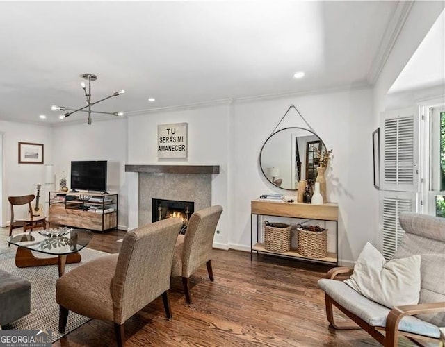 living room with a notable chandelier, crown molding, recessed lighting, wood finished floors, and a lit fireplace