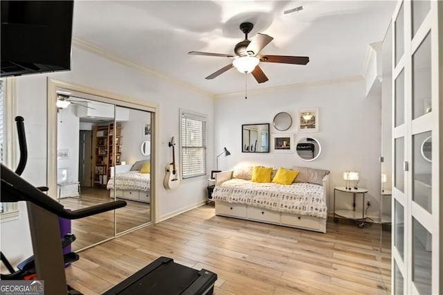 exercise room featuring a ceiling fan, crown molding, light wood-style flooring, and baseboards