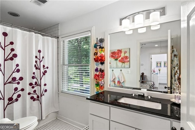 bathroom with toilet, vanity, visible vents, and a healthy amount of sunlight