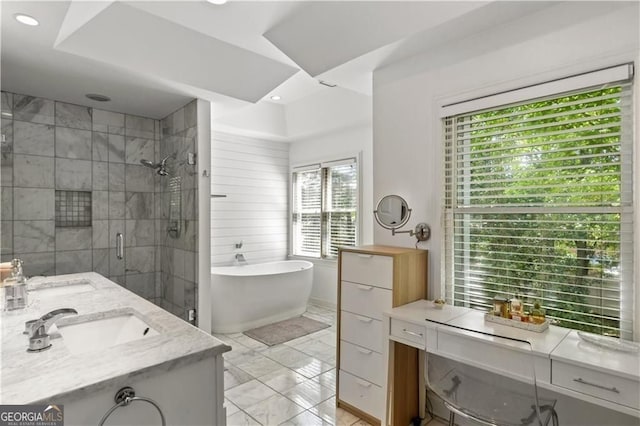 full bathroom featuring double vanity, a freestanding tub, a sink, and a shower stall