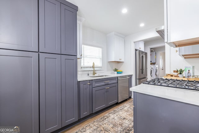 kitchen featuring stainless steel appliances, separate washer and dryer, a sink, and light countertops