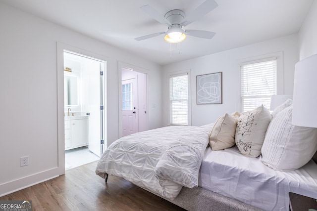 bedroom featuring ensuite bath, multiple windows, wood finished floors, and baseboards